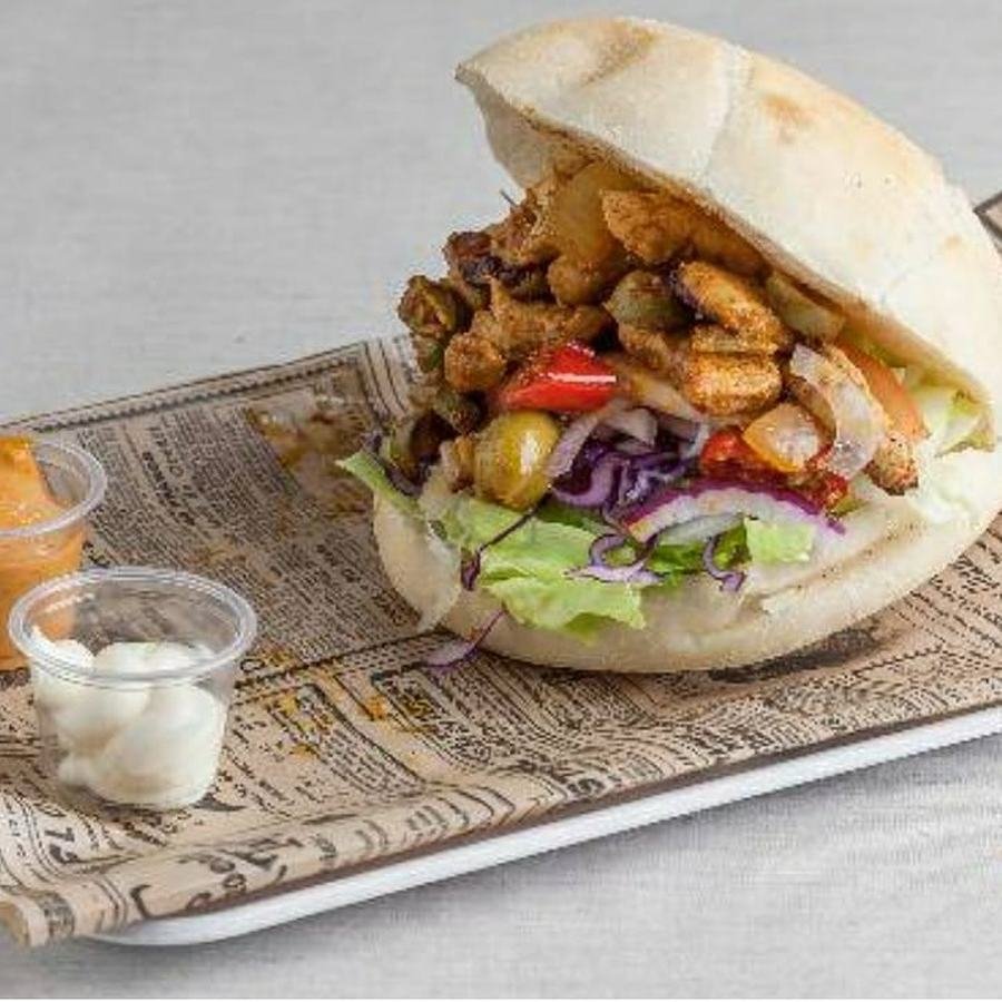 Sandwich kebab garni de viande grillée, salade, oignons rouges et olives, servi avec deux sauces